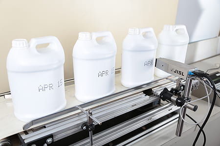 four white plastic bottles on gray stainless steel machine thumbnail