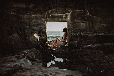 woman sitting on stone near body of water thumbnail
