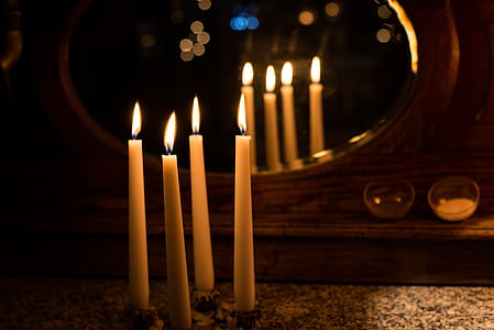four white lighted stick candles near the mirror thumbnail