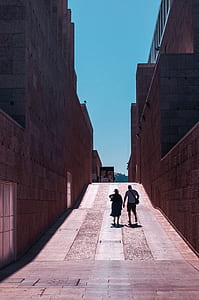 man and woman walking between buildings thumbnail