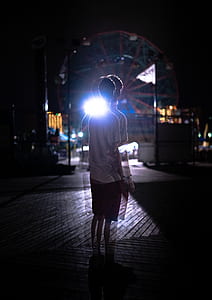 boy standing in front of ferris wheel at night time thumbnail