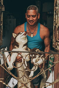 man carrying two Siberian huskies thumbnail