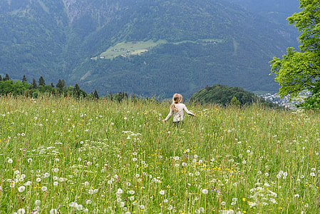 girl in white long-sleeve shirt walking on flower field during daytime thumbnail