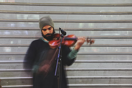 man playing violin standing near wall thumbnail