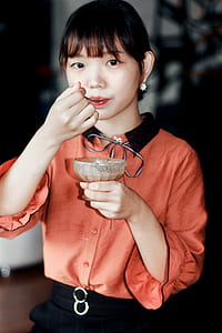 Woman in Orange Dress Holding Brown Liquid Filled Glass Cup thumbnail