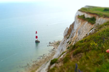 , nature photography of cliff overlooking white and red lighthouse thumbnail