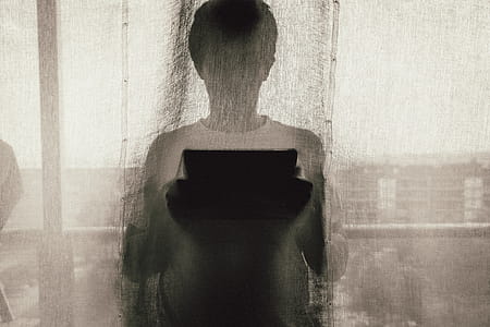 Man Standing Holding A Tablet Behind Curtain thumbnail