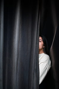 woman hiding behind black curtain thumbnail