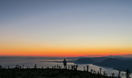silhouette of man standing on cliff looking coastlines landscape photography thumbnail