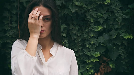 woman wearing white button-up top in front of green leafed plant thumbnail