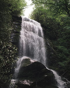 waterfalls beside green leafed trees during daytime thumbnail
