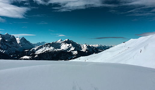 snow covered mountains under white clouds and blue sky thumbnail