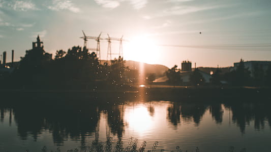 Silhouette of Building and Trees Near Body of Water during Golden Hour thumbnail