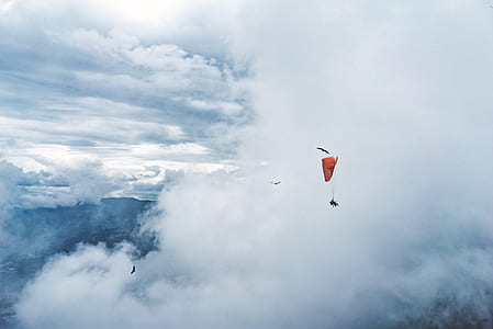 pan wearing parachute near clouds during daytime thumbnail