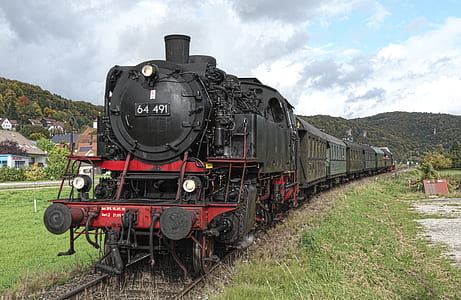 black and red steam-engine train under cloudy sky thumbnail