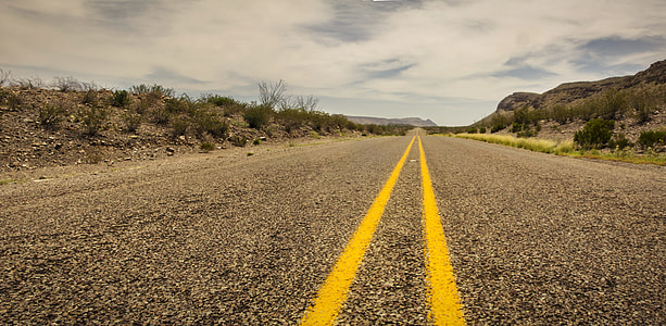 concrete road beside rock hill under cloudy sky at daytime thumbnail