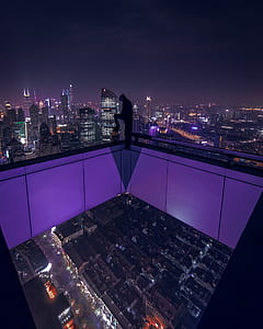 person sitting on the edge of railing under dark sky thumbnail