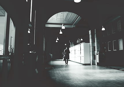 Silhouette of a Person Walking on a Grey Floor Tiles Beside White Cabinet in Dark Room thumbnail
