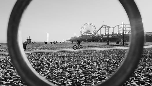 person riding bicycle from afar looking through ring in grayscale photography thumbnail