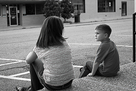 grayscale photo of boy and girl sitting on curb during daytime thumbnail