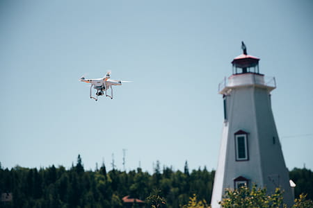 A drone in flight near a lighthouse with clear sky in the background thumbnail