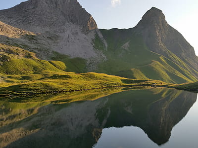 calm water near green mountain at daytime thumbnail