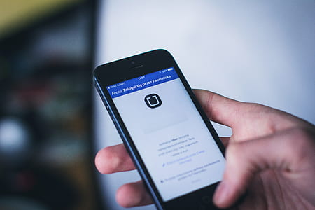 person holding iPhone displaying mobile application thumbnail