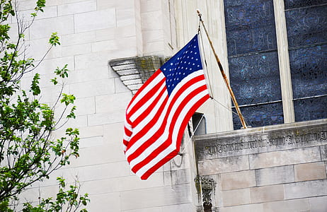 U.S.A. flag on pole mounted on gray building wall thumbnail