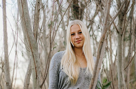 woman standing near gray bare trees during daytime thumbnail