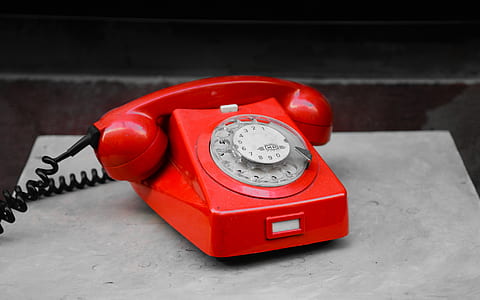 red rotary telephone on gray surface thumbnail