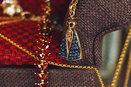 gold-colored blue gemstone pendant necklace beside brown knit textile thumbnail