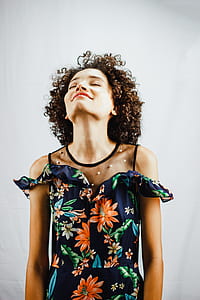 woman closing her eyes while standing near white wall thumbnail
