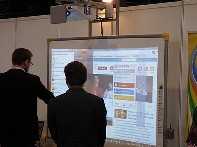 two men facing projector canvass with turned on projector on top ] thumbnail
