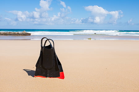 pair of black-and-red flippers on seashore during daytime thumbnail