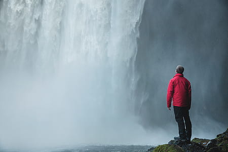 standing man watching waterfalls during day thumbnail