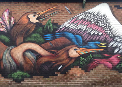Mural of two birds attacking another bird on a brick wall in New Cross, Manchester. thumbnail