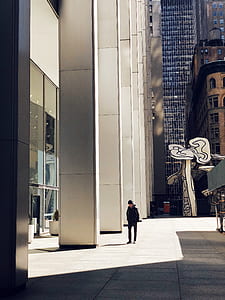 man standing on concrete pavement beside high building during daytime thumbnail