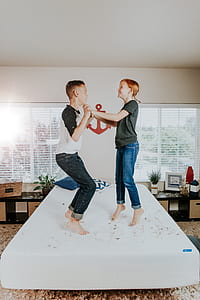 boy and girl jumping on bed inside room thumbnail