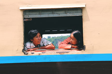 two women leaning at window thumbnail