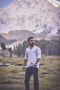 Man in Grey V-neck Long-sleeved Shirt With Blue Denim Jeans Behind White Mountain thumbnail