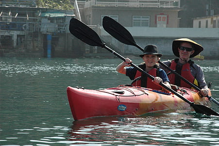 man and boy on red kayak paddling thumbnail