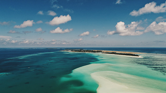 island surrounded by sea under blue and white sky during daytime thumbnail