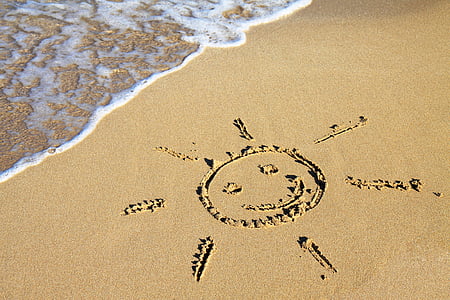 photo of sun illustration on sand near body of water during daytime thumbnail