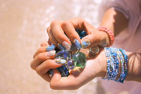 person holding green and purple gel beads during daytime thumbnail