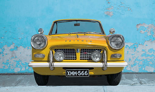 classic yellow car parked near teal wall thumbnail