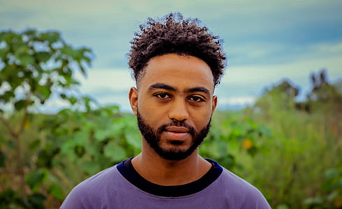 man in purple shirt near trees thumbnail
