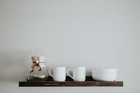 brown wooden wall-mounted shelf with one clear glass pour over pitcher, two white ceramic mug, and two bowls thumbnail