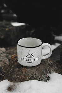 closeup photo of black and white a simple life text-printed mug on brown rock thumbnail