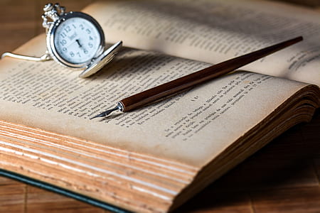 black pen and silver-colored pocket watch on book thumbnail