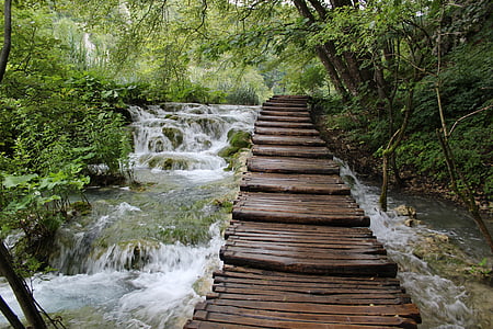 time-lapse photography of brown wooden bridge above waterfalls thumbnail